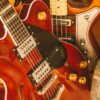 Vertical shot of three brown electric guitars showcasing details, strings, and shiny finishes.