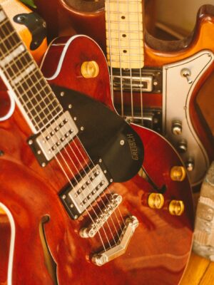 Vertical shot of three brown electric guitars showcasing details, strings, and shiny finishes.