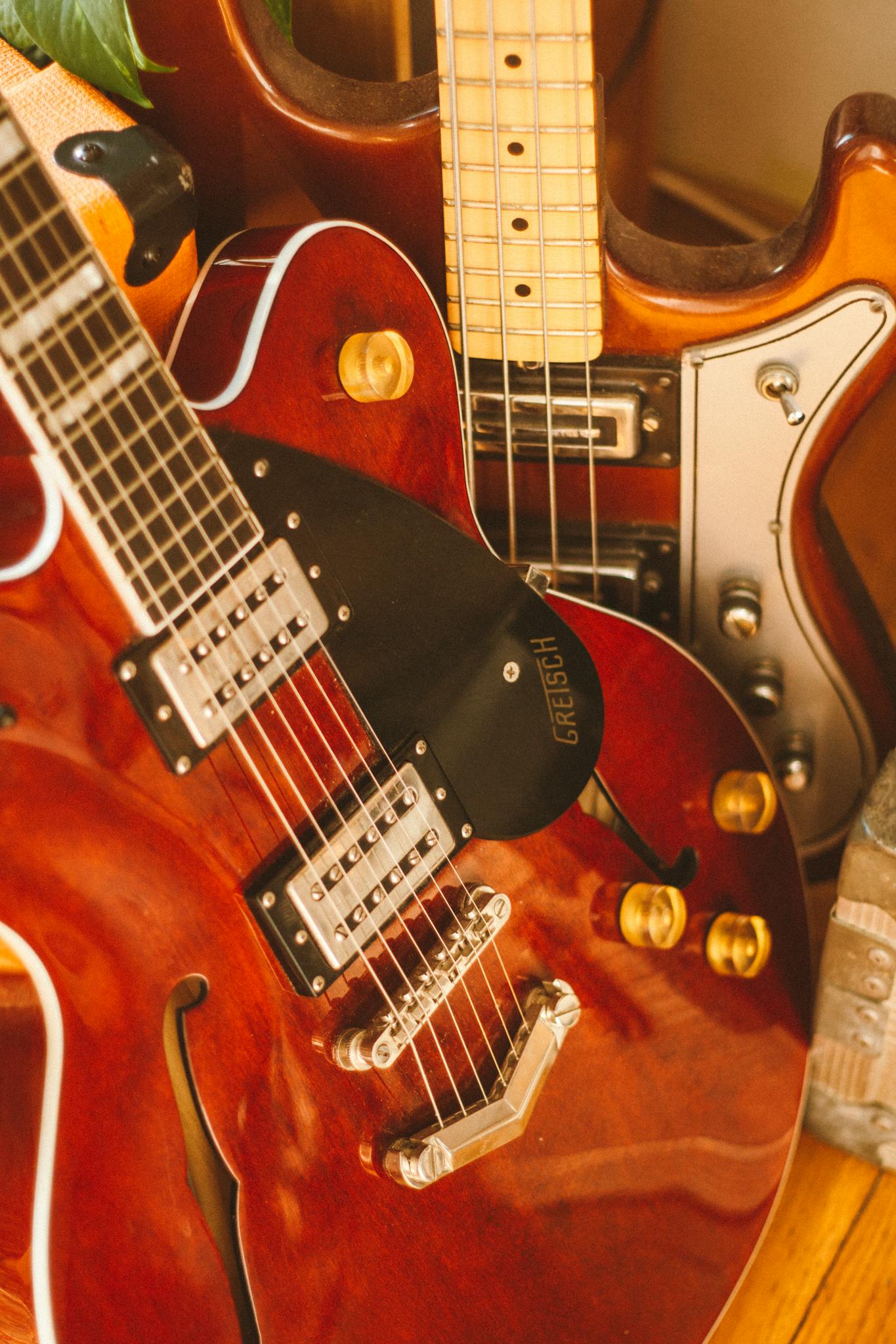 Vertical shot of three brown electric guitars showcasing details, strings, and shiny finishes.