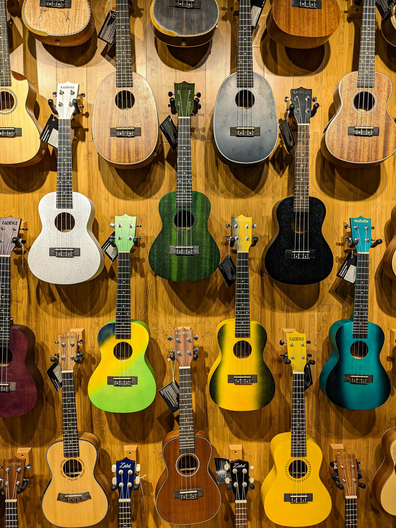 Vibrant ukuleles in various colors hanging on a wooden wall, showcasing musical diversity.