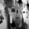 Wall-mounted acoustic guitars in a music shop, black and white photo.